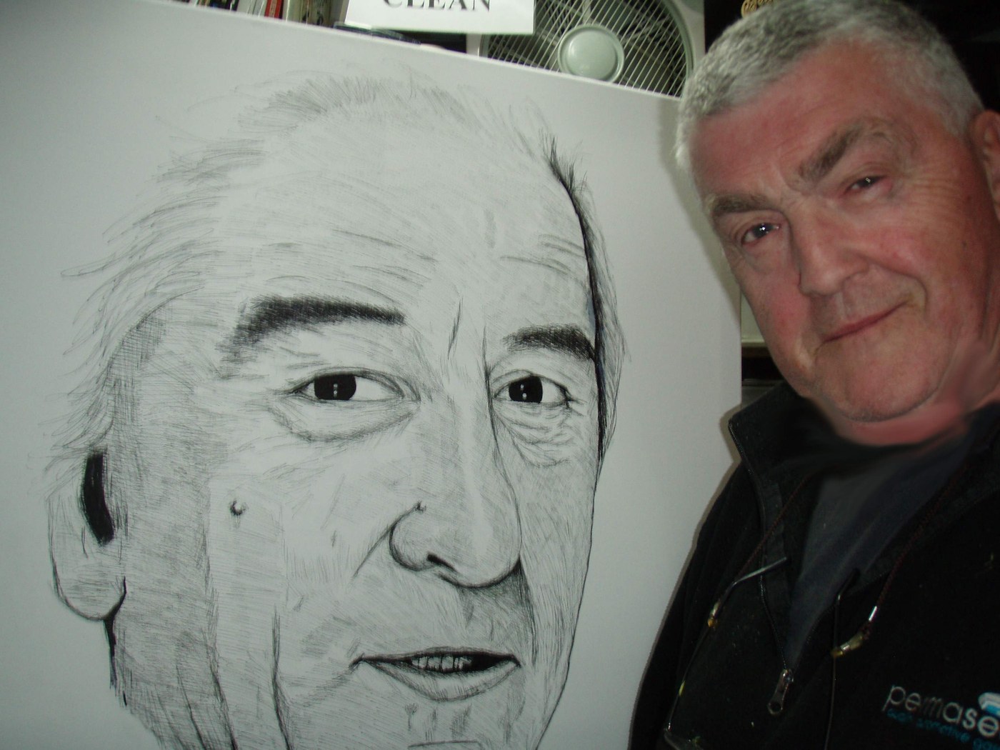 Colin Bridle beside a large pencil portrait