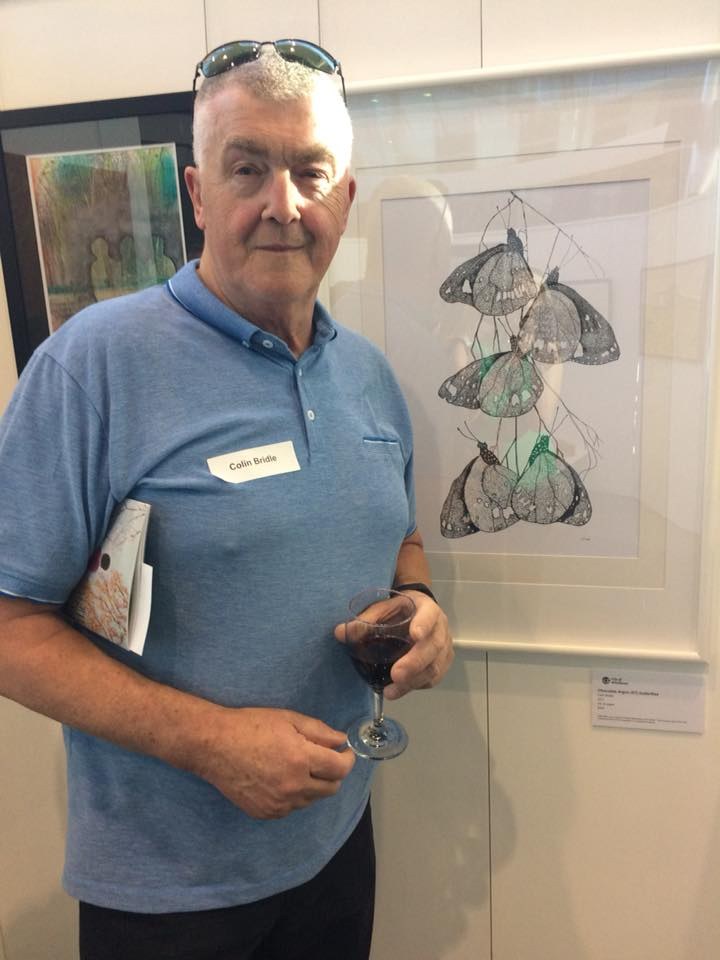 Colin Bridle standing beside framed butterfly artwork